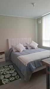 a bedroom with a bed with blue sheets and a window at Departamento Nuevo 1D1B con estacionamiento sobre stripcenter y supermercado in Los Ángeles