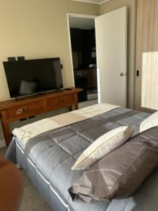 a bedroom with a large bed and a flat screen tv at Departamento Nuevo 1D1B con estacionamiento sobre stripcenter y supermercado in Los Ángeles +6 photos