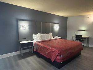 a bedroom with a large bed with a red blanket at Roseville Inn in Roseville +2 photos