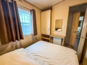 a small bedroom with a bed and a window at 6 Berth Caravan With Side Decking At Suffolk Sands Holiday Park Ref 45054C in Felixstowe +14 photos