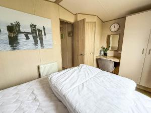 Cosy 6 Berth Caravan With Side Decking At Kessingland Beach, Suffolk Ref 90031Sv في Benacre: غرفة نوم بسرير ومغسلة وساعة +18 صورة