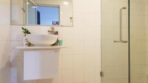 een witte badkamer met een wastafel en een douche bij Chic Studio Huế Homestay in Hue