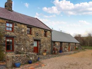 una vecchia casa in pietra con una porta rossa e un vialetto di The Crog Loft - Uk45652 a Rhiw