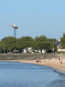 a group of people on a beach near the water at T2 a St Nazaire, 500 mètres de la plage in Saint-Nazaire