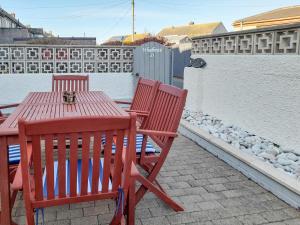 twee rode stoelen en een tafel op een patio bij Wheelhouse 21 in Amble