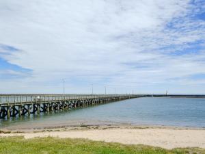 een lange pier in het water met een strand bij Wheelhouse 21 in Amble