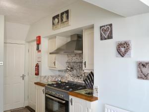 a kitchen with white cabinets and a stove top oven at Wheelhouse 21 in Amble