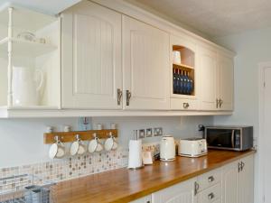 a kitchen with white cabinets and a wooden counter top at Wheelhouse 21 in Amble