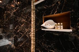 uno scaffale con cosmetici su una parete di marmo di Eterea Wellness Suites a Montescaglioso Altre 18 foto