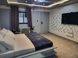 a bedroom with a bed and a flat screen tv at Ndouha House in Bafoussam