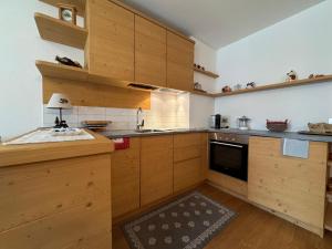 a large kitchen with wooden cabinets and a sink at Suite Panorama in Valdisotto