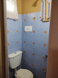a bathroom with a toilet and a blue tiled wall at Depto San Clemente 3 in San Clemente del Tuyú