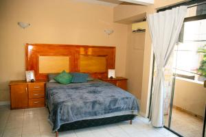 a bedroom with a bed with a wooden headboard and a window at GuestHouse Encanto del Centro in Encarnación