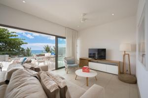 a living room with a couch and a tv at Les Estivales Beachfront Suites & Penthouses by LOV Mauritius in Trou aux Biches