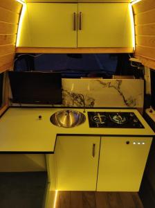T4 Camper في أغادير: مطبخ اصفر مع مغسلة وموقد