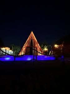 un edificio in legno di notte con luci blu di LIMMAT Chalés a Hora