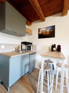 cocina con fregadero y encimera con taburetes en Le Parmelan - Sur la route d'Annecy, en Alby