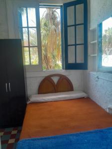 a bed in a room with two windows at Paloma in Atlántida