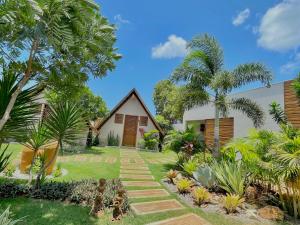a house with a garden and palm trees at Pousada Villa di Luna in São Miguel do Gostoso