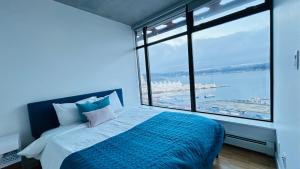 ein Schlafzimmer mit einem Bett und einem großen Fenster in der Unterkunft Ocean and Mountain View Home - Downtown Vancouver in Vancouver