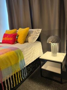 Stylish Private Rooms في بيرجس هيل: سرير مع وسائد ملونة وطاولة جانبية