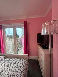 a bedroom with pink walls and a bed and a window at Paignton seafront Apartment with Private Garden ,FREE Private Car Space FREE WIFI ,No kitchen but Fridge Tea coffee Towels YES Double & Single bed YES Reception to help you YES Opposite the Beach Yes in Paignton