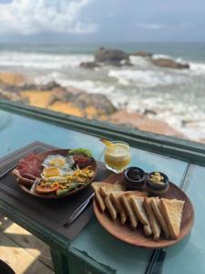 Manta Beach Resort & Ayurvedic Wellness Centre في غالي: طبق من الطعام مع البيض والخبز المحمص والمحيط