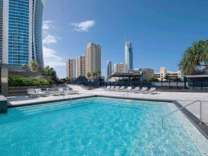 a swimming pool with chairs and a city skyline at Mantra Circle On Cavill in Gold Coast