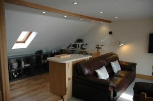 a living room with a leather couch and a kitchen at Harbourside in Tobermory