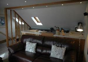 a brown leather couch in a living room with a kitchen at Harbourside in Tobermory