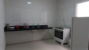 een witte keuken met een fornuis en een wastafel bij BJLAPA Residence in Bom Jesus da Lapa