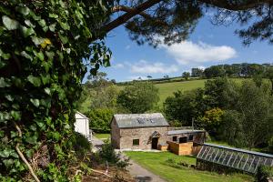 eine Steinscheune mit Gewächshaus auf einem Feld in der Unterkunft Coombe Farm Goodleigh - The Stables in Goodleigh