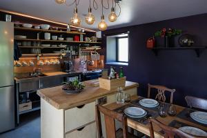 eine Küche mit einem Tisch mit Stühlen und einem Kühlschrank in der Unterkunft Coombe Farm Goodleigh - The Stables in Goodleigh