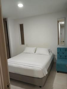 Jardin imperial, habitaciones para tu disfrute y descanso en apto familiar في كارتاهينا دي اندياس: غرفة نوم بسرير أبيض وكرسي أزرق