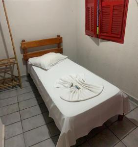 a bed in a room with a white blanket on it at Hotel Santo Antoninho in Goiânia