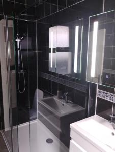 a black tiled bathroom with a sink and a shower at Caminetto in Croydon