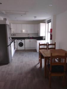 a kitchen with white cabinets and a table and chairs at Caminetto in Croydon