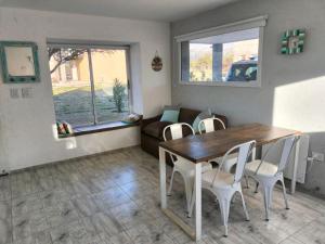 a dining room with a table and chairs and a couch at Atardeceres del dique in Cortaderas