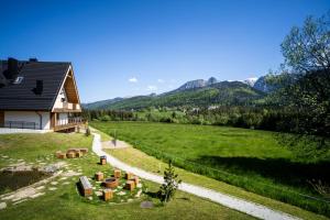 a house in a field with mountains in the background at Apartament Panorama M05 by Apart Concept Podhale in Kościelisko