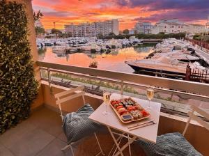 a plate of food on a table on a balcony with a marina at Magnifique T2 au calme avec une superbe vue sur le port in Canet-en-Roussillon