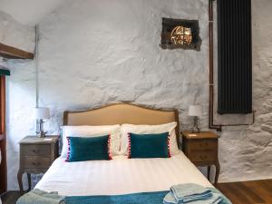 ein Schlafzimmer mit einem Bett mit Kissen und zwei Nachttischen in der Unterkunft Ty Chwiad - Uk45650 in Rhiw