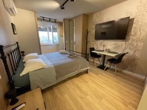 a bedroom with a bed and a desk and a television at Piazza Downtown Cozy Studio in Tirana