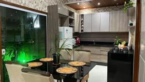 una cucina con un tavolo nero con sedie e una cucina con un bancone di Casa Bello encanto a Cachoeira Paulista