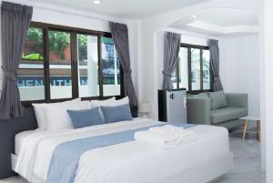 a bedroom with a large white bed and a chair at Brickotel Naithon Beach in Nai Thon Beach