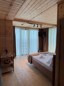 Un dormitorio con una cama grande en una habitación con ventanas. en Kvirike Hills Hotel, en Kobuleti