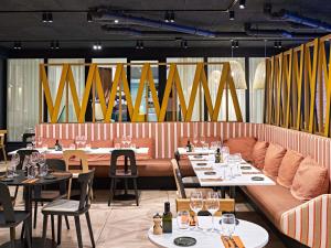Un comedor con mesas, sofás y sillas. en Novotel Rouen Centre Cathédrale, en Rouen