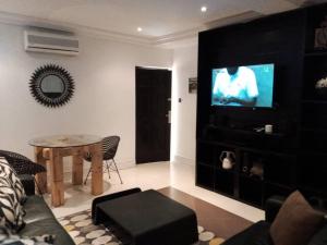 a living room with a television and a table at Etikette Homes in Accra