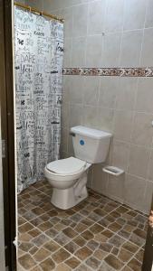 a bathroom with a toilet and a shower curtain at Cabaña la Hamaca Grande un encuentro con la naturaleza in El Zaino