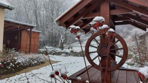 CserépváraljaにあるFaluvégi Vendégházの小屋の前に木製の車輪がある雪に覆われた庭