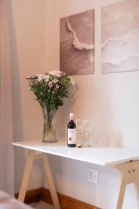a table with a bottle of wine and a vase of flowers at Mountain and Tides in Kleinmond